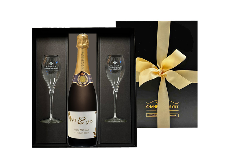 A bottle of Champagne in a black gift box with flutes. Label is to celebrate a wedding.